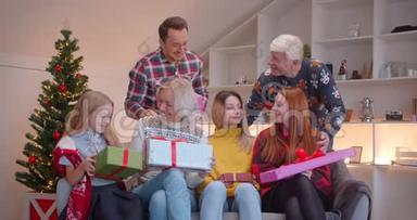 一家人坐在沙发上互相赠送圣诞礼物，一家人则会送圣诞礼物